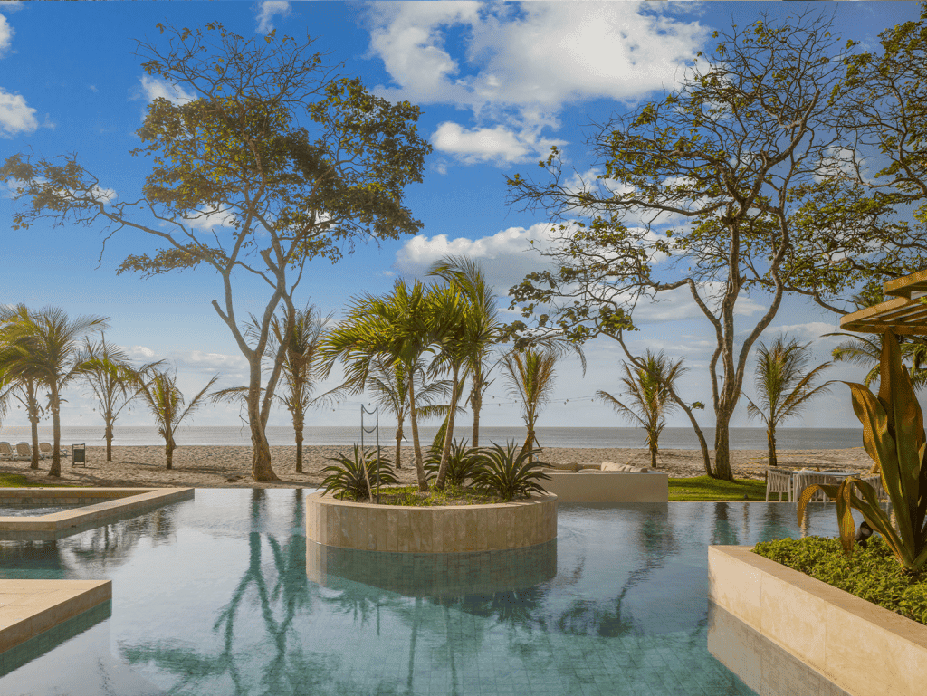 Beachfront pool at Surfside Playa Caracol, Panama, with palm trees and ocean views. Perfect for rela.