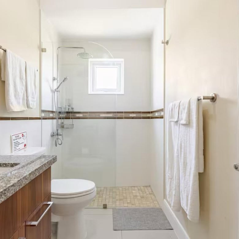 Modern bathroom in luxury Jamaican seaside home with white tiles and wooden accents.