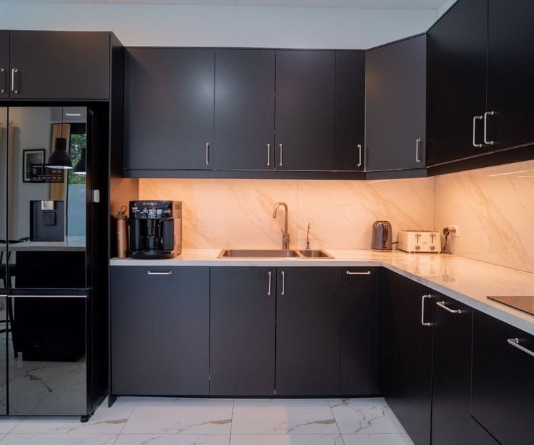 Modern black kitchen with marble countertops, coffee machine, and sleek cabinetry in a luxury villa.