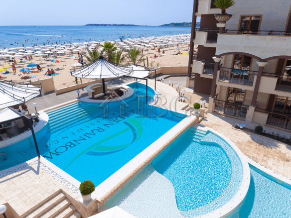 Beautiful pool area with sun loungers and shaded cabanas overlooking the sandy beach. Perfect for re.