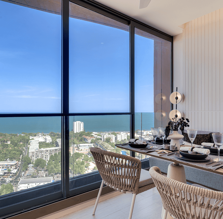 Ocean view dining space in Hua Hin, Thailand with stylish furniture and large windows.