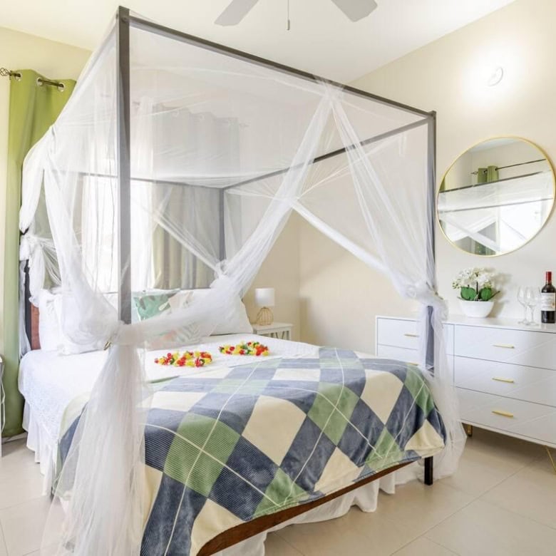 Elegant bedroom with a four-poster bed and mosquito net in a tropical home.