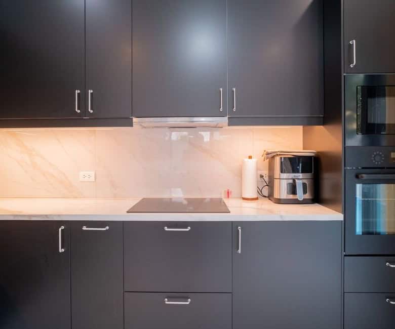 Modern black kitchen cabinets with built-in oven and microwave.