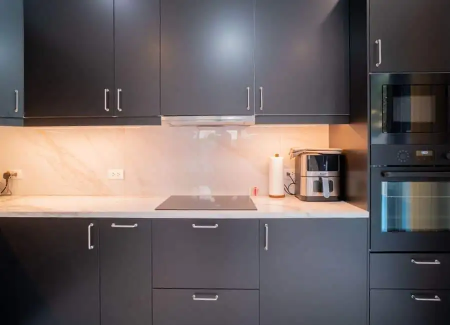 Modern kitchen with sleek black cabinets and built-in appliances. Modern black kitchen cabinets with built-in oven and microwave.