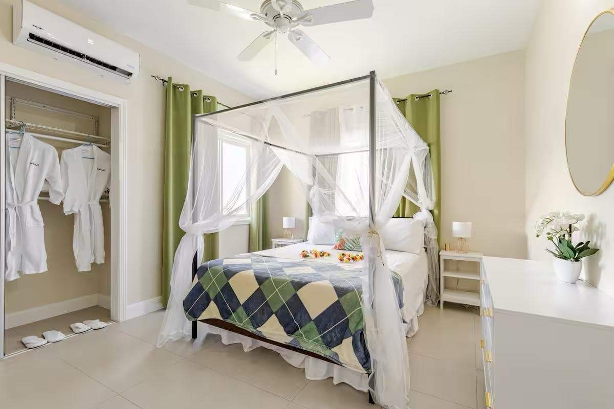 Luxury 3 Bed House in Jamaica Elegant bedroom with a canopy bed and ocean views.