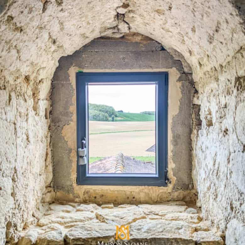 View of the countryside through a stone window in a historic building.