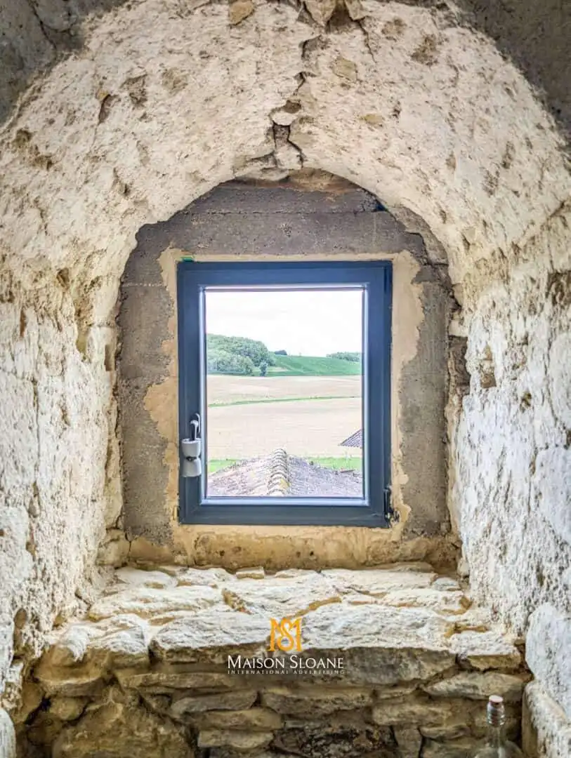 View of the countryside through a stone window in a historic building.