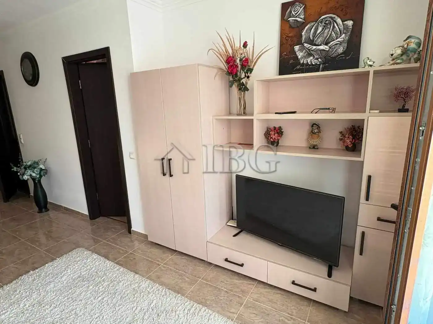 Modern living room with beige storage unit, decorative flowers, and wall art.