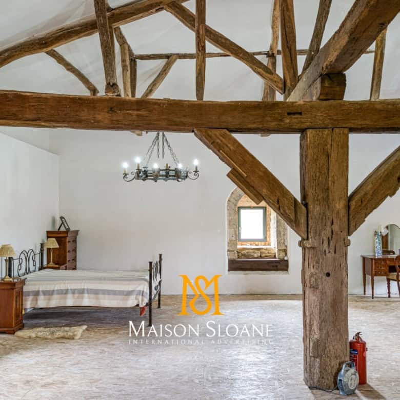 Spacious bedroom with rustic wooden beams and vintage furniture in a luxurious French countryside es.