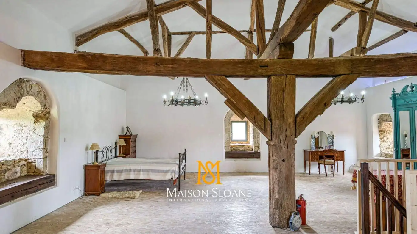 Spacious bedroom with rustic wooden beams and vintage furniture in a luxurious French countryside es.