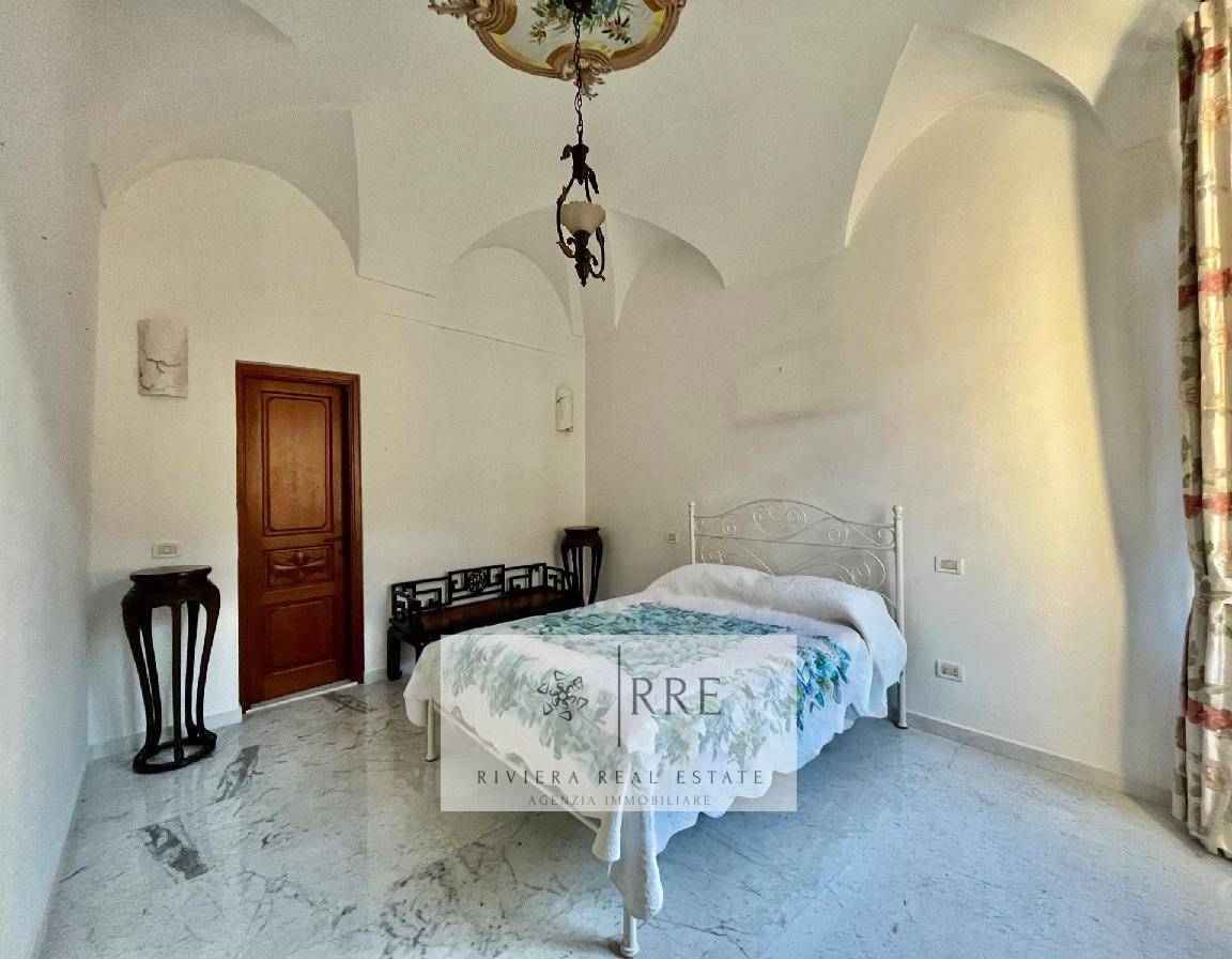 Spacious bedroom featuring white walls, a wrought iron bed, and elegant decor in a bright, airy room.