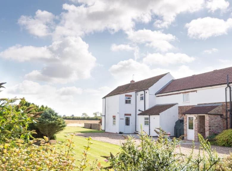 Beautiful countryside house with a well-maintained garden and blue sky backdrop.