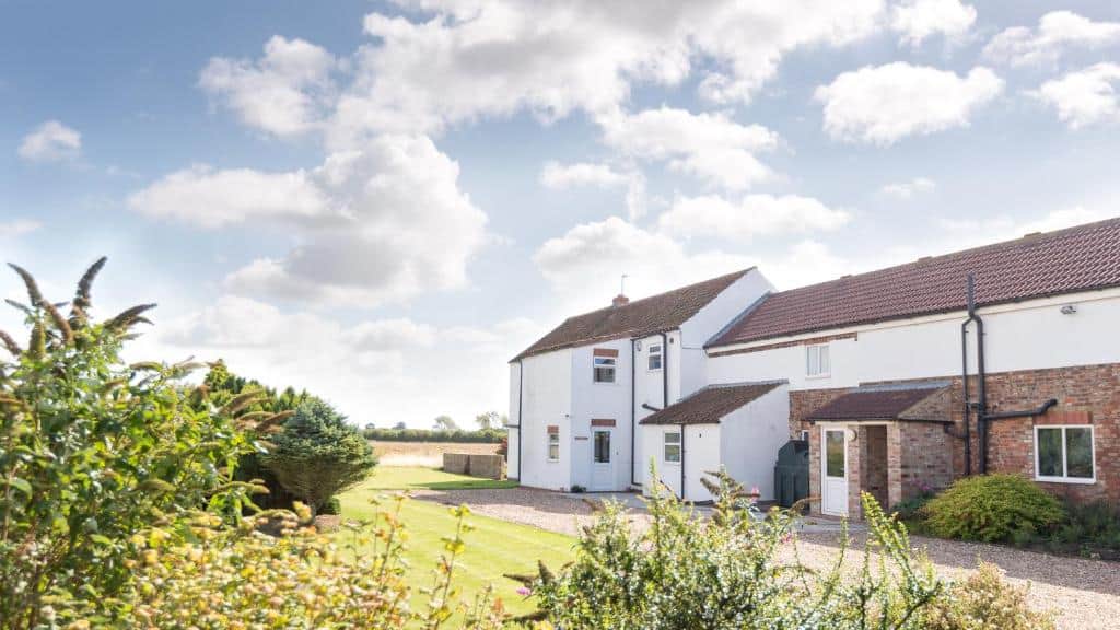 Modern countryside home with lush garden and clear sky Beautiful countryside house with a well-maintained garden and blue sky backdrop.