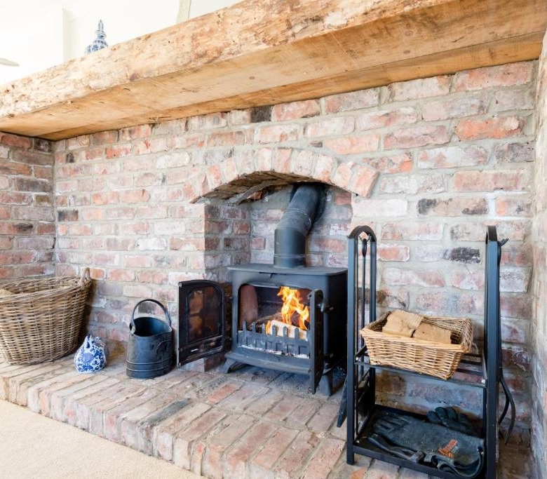 Traditional brick fireplace with a warm fire and wood storage area.