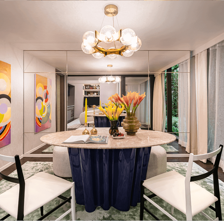 Stylish Bangkok dining room with modern art, chandelier, and lush greenery outside.
