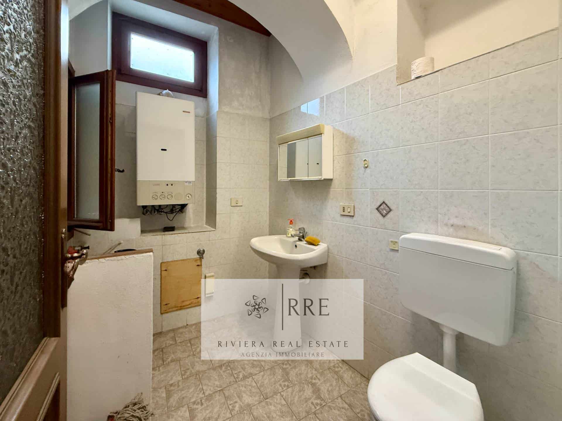 Bathroom with white sink, toilet, and small window for ventilation.