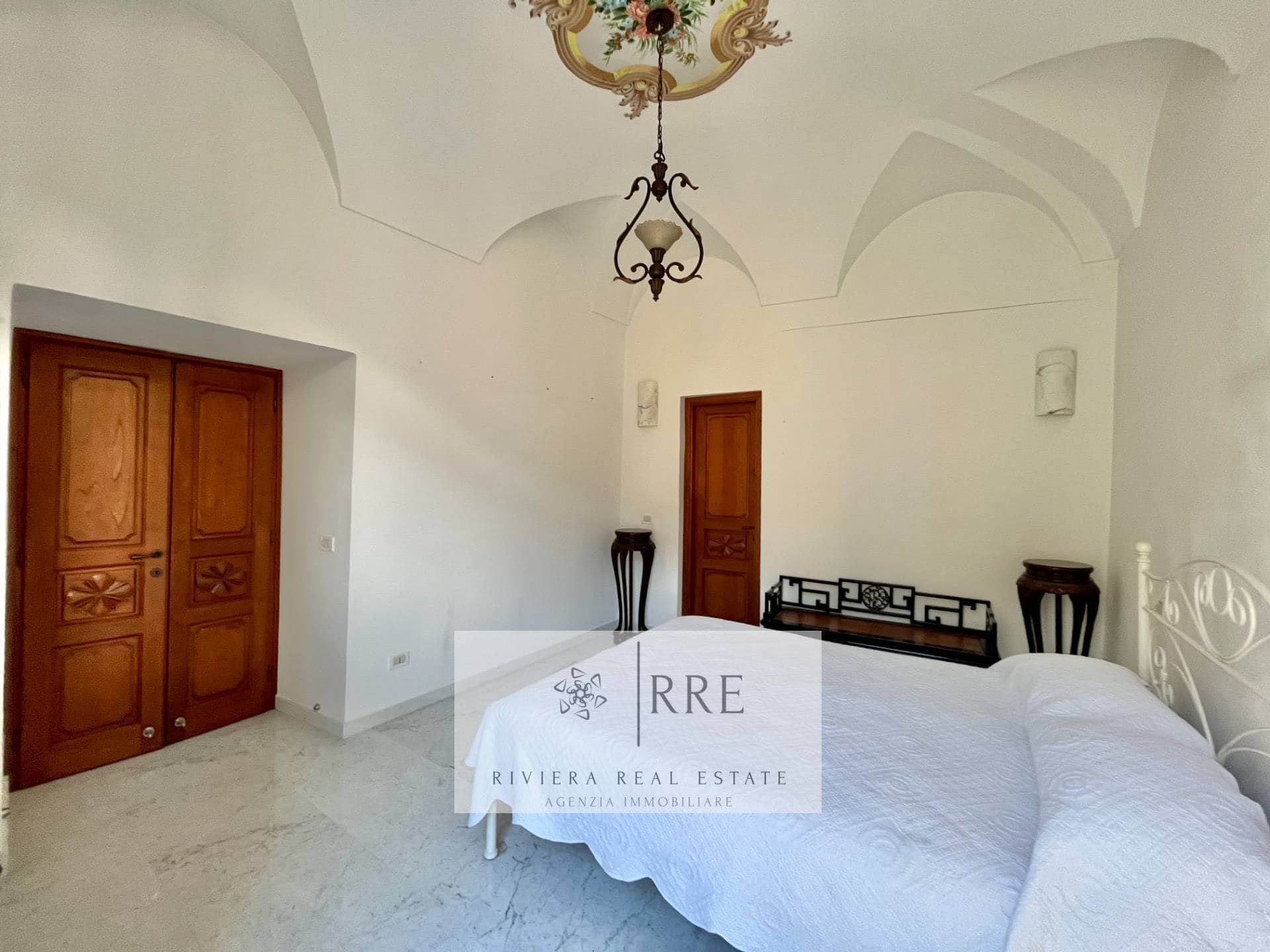 Spacious bedroom with white walls, wooden closet doors, and classic decor.
