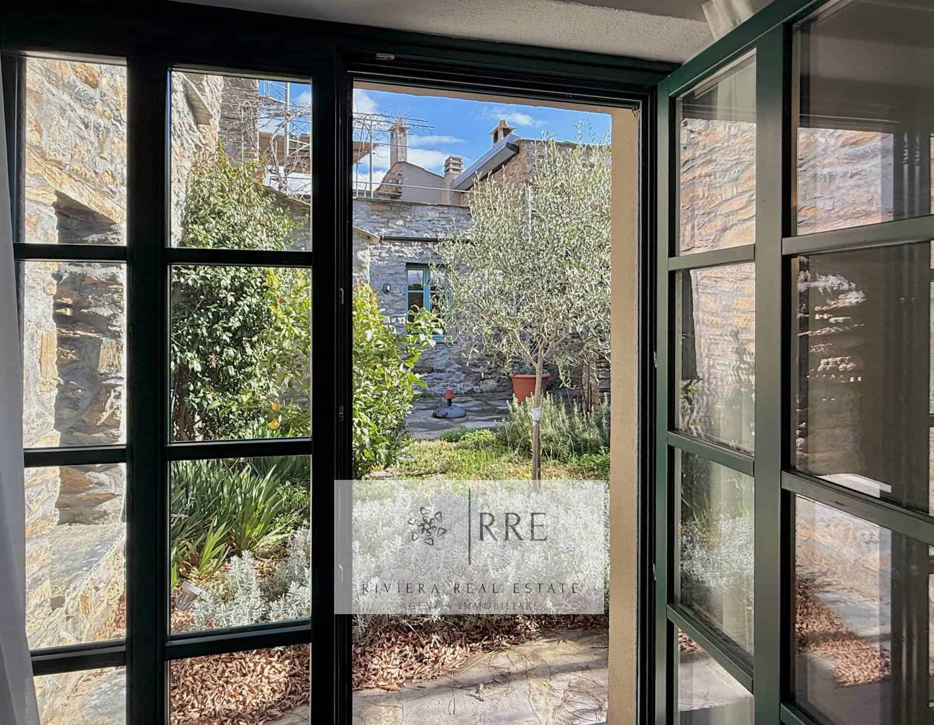 View of a charming house and garden seen through glass doors.