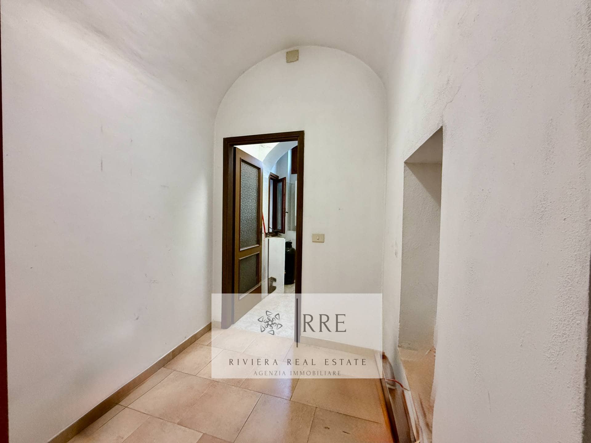 Interior hallway with white walls, arched ceiling, and wooden doorframes in a contemporary home.