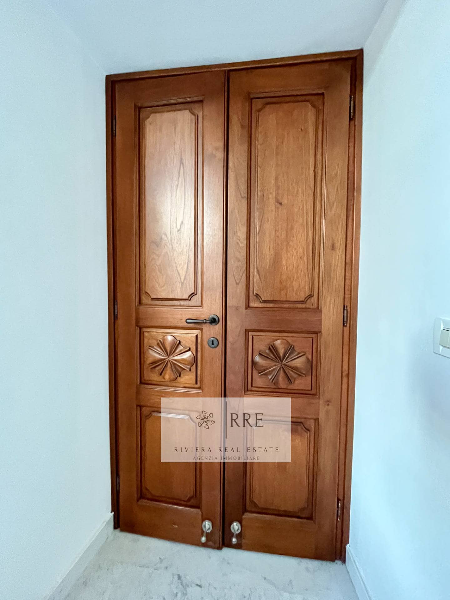 Interior wooden door with decorative panels and black handle.