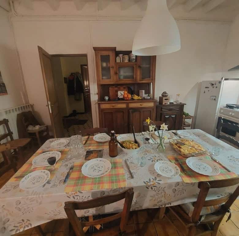 Cozy farmhouse dining area with a large table set for a family meal in Madiran Village, France.
