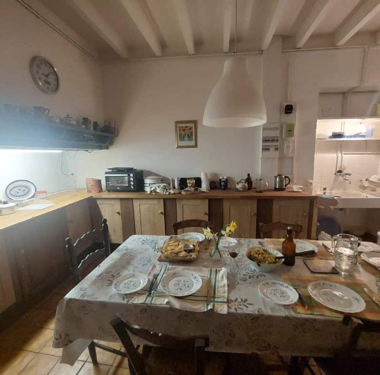 Cozy farmhouse kitchen with rustic wooden cabinets and a large dining table set for a family meal.