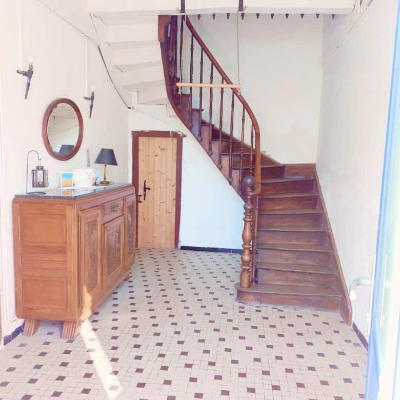 Cozy farmhouse interior with wooden staircase and vintage furniture in Madiran village, France.