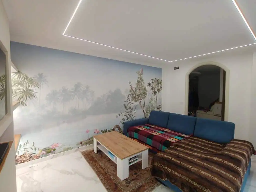 Bright living space with tropical mural and modern lighting in Bernalda Italy.