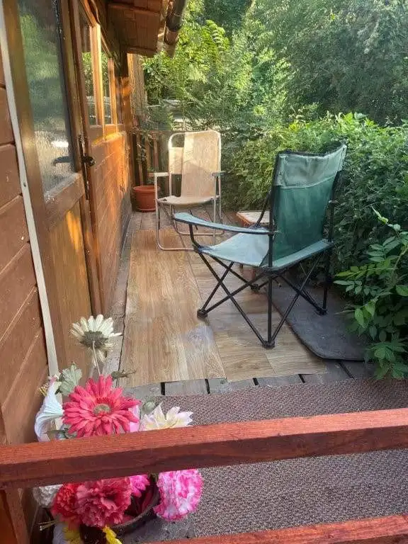 Cozy outdoor porch with seating area in a Bulgarian countryside home. Surrounded by lush greenery an.