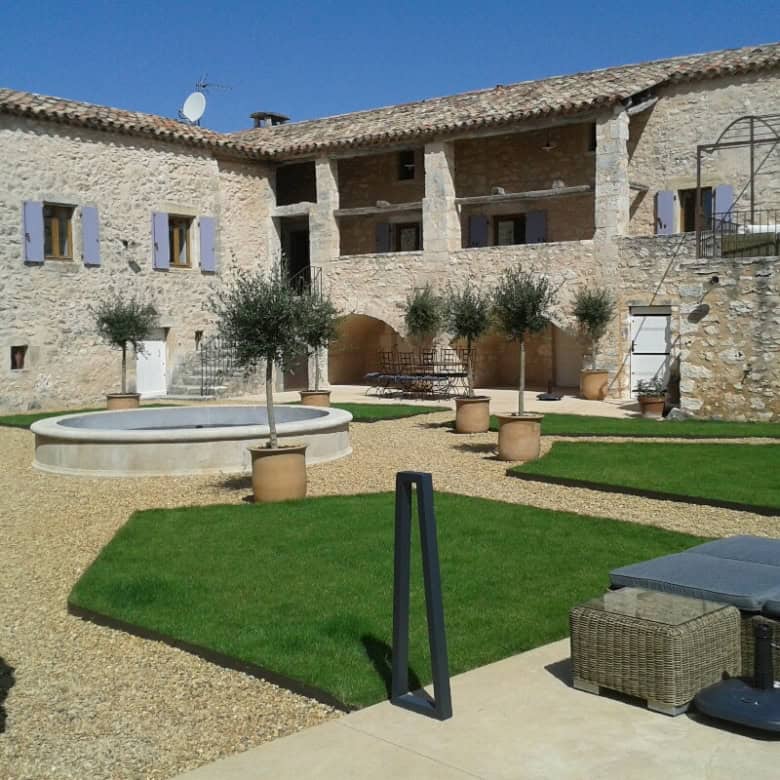 Elegant estate with lush gardens and outdoor seating in Goudargues, France.