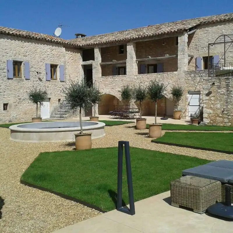 Elegant estate with lush gardens and outdoor seating in Goudargues, France.