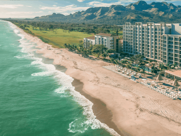Beachfront view of Surfside - Playa Caracol, Panama with ocean, sand, and resort buildings.