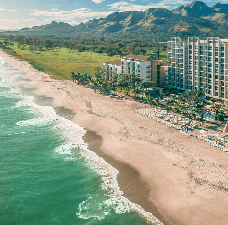 Beachfront view of Surfside - Playa Caracol, Panama with ocean, sand, and resort buildings.