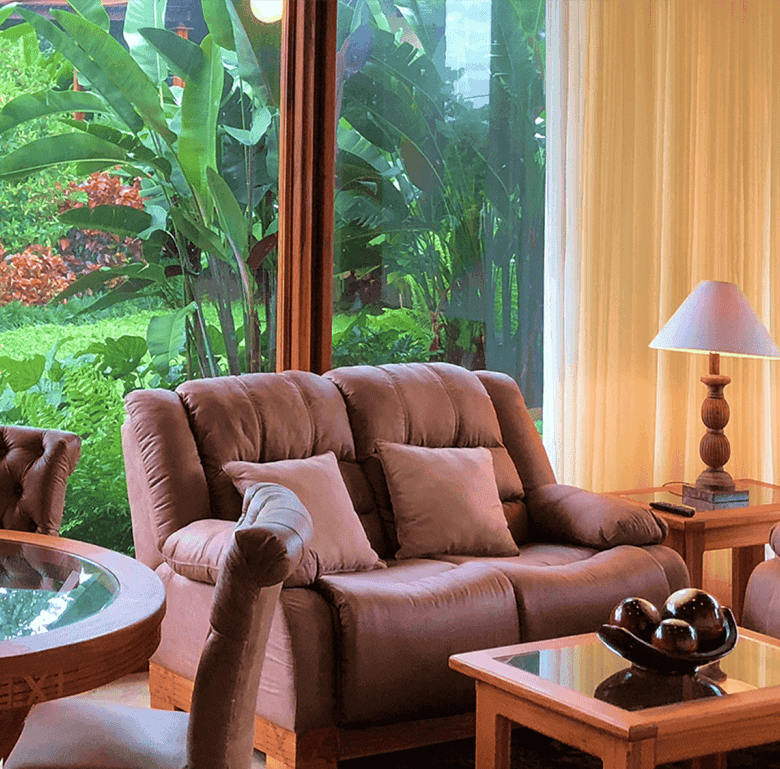 Living room with large windows overlooking lush greenery in Costa Rica.
