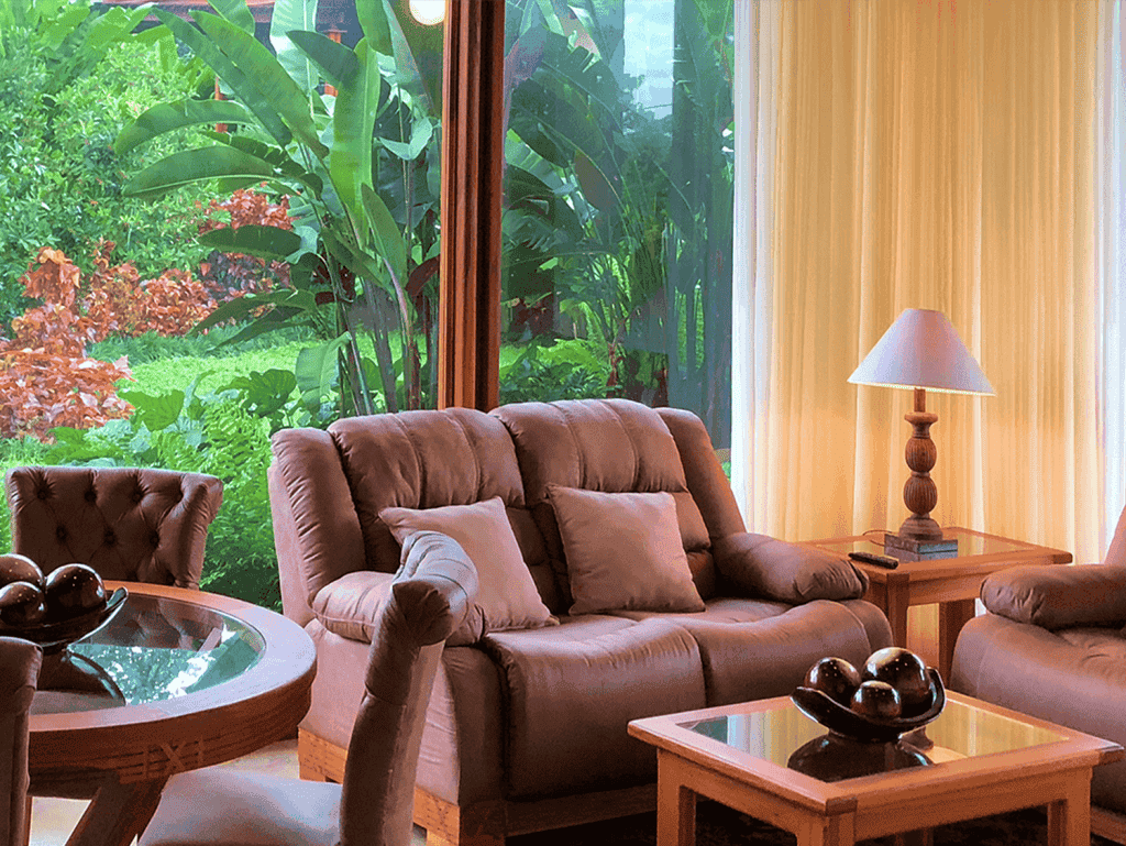 Living room with large windows overlooking lush greenery in Costa Rica.