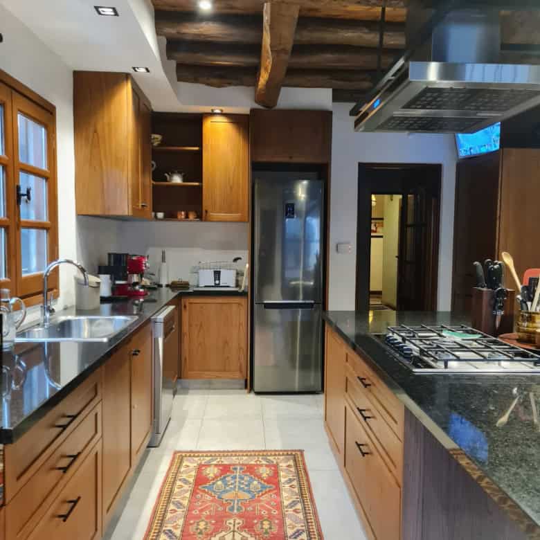 Rustic kitchen featuring wooden cabinets, stainless steel appliances, and a colorful rug for a warm,.