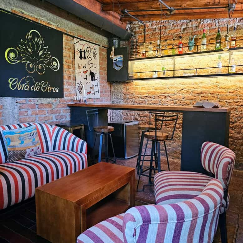 Cozy bar with exposed brick walls, colorful striped furniture, and ambient lighting. Perfect for soc.
