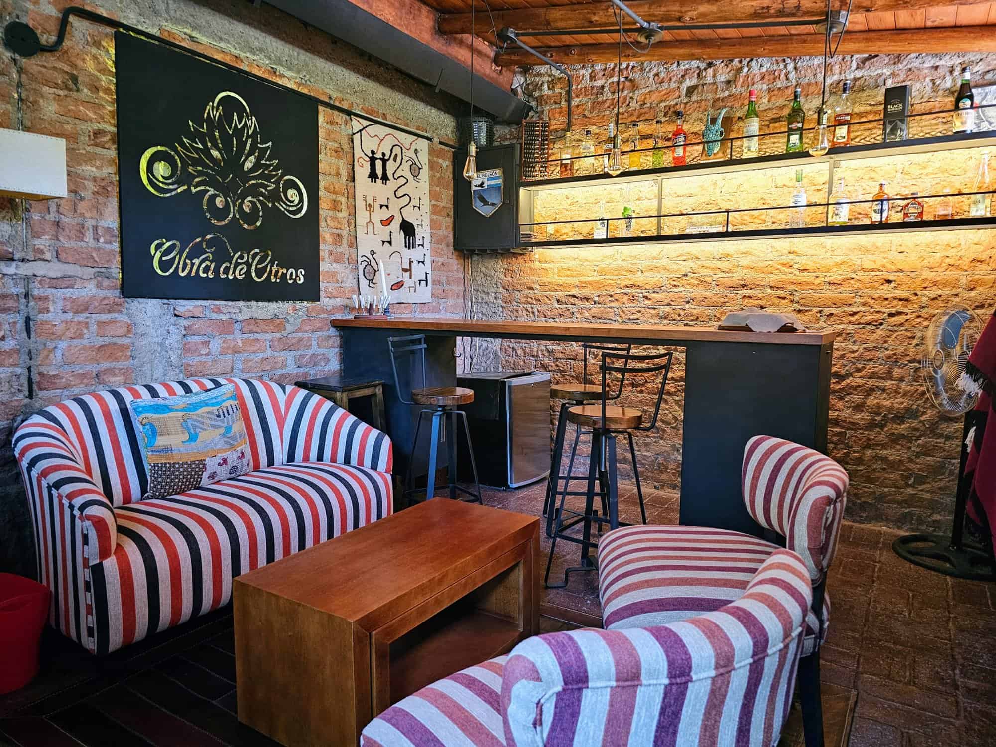 Charming Bar Interior with Vintage Decor Cozy bar with exposed brick walls, colorful striped furniture, and ambient lighting. Perfect for soc.