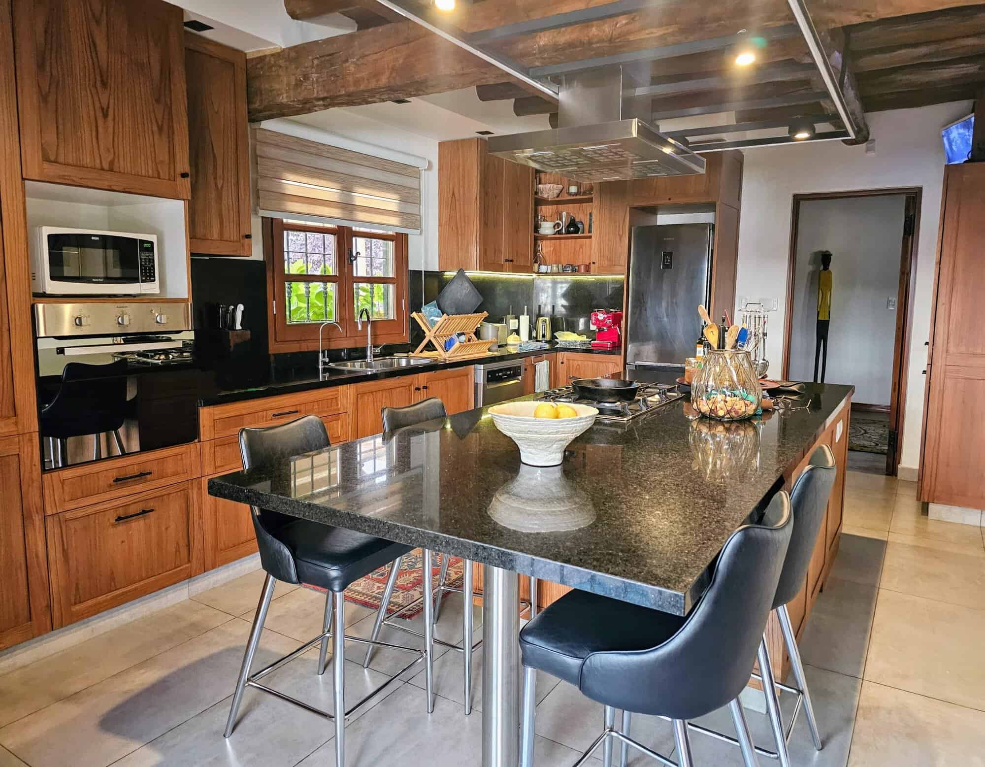 Modern wooden kitchen with island and black countertops, bright natural light, and contemporary appliances. Modern wooden kitchen with island and black countertops, bright natural light, and contemporary appl.