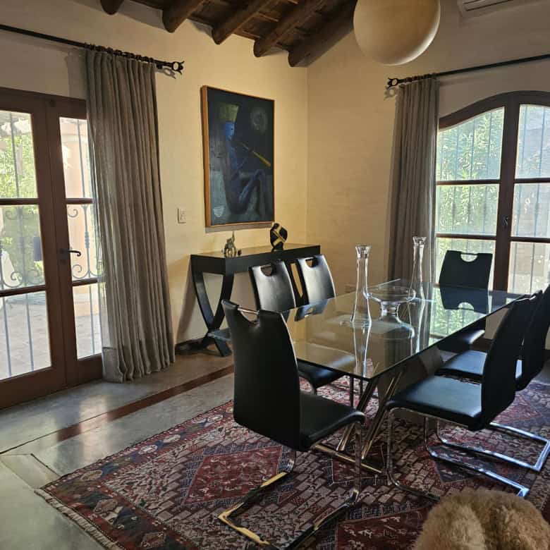 Spacious dining area with glass table, black chairs, and natural light from large windows.