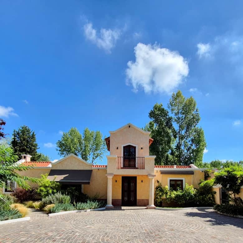 Elegant Spanish villa with lush garden and swimming pool in a sunny setting.