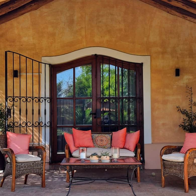 Outdoor patio with wicker chairs and a table, perfect for relaxing and enjoying the garden view.