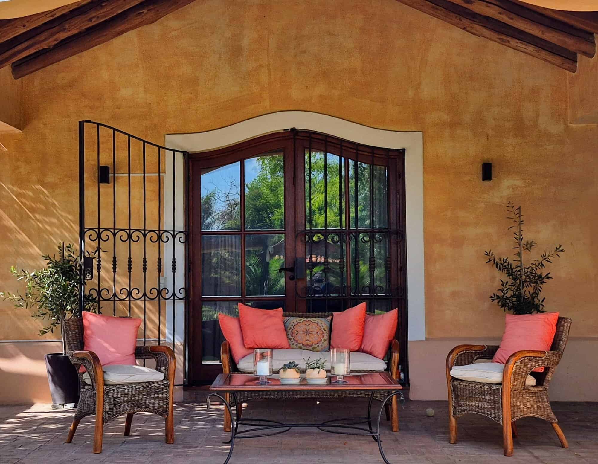 Cozy outdoor patio with wicker furniture and colorful cushions Outdoor patio with wicker chairs and a table, perfect for relaxing and enjoying the garden view.