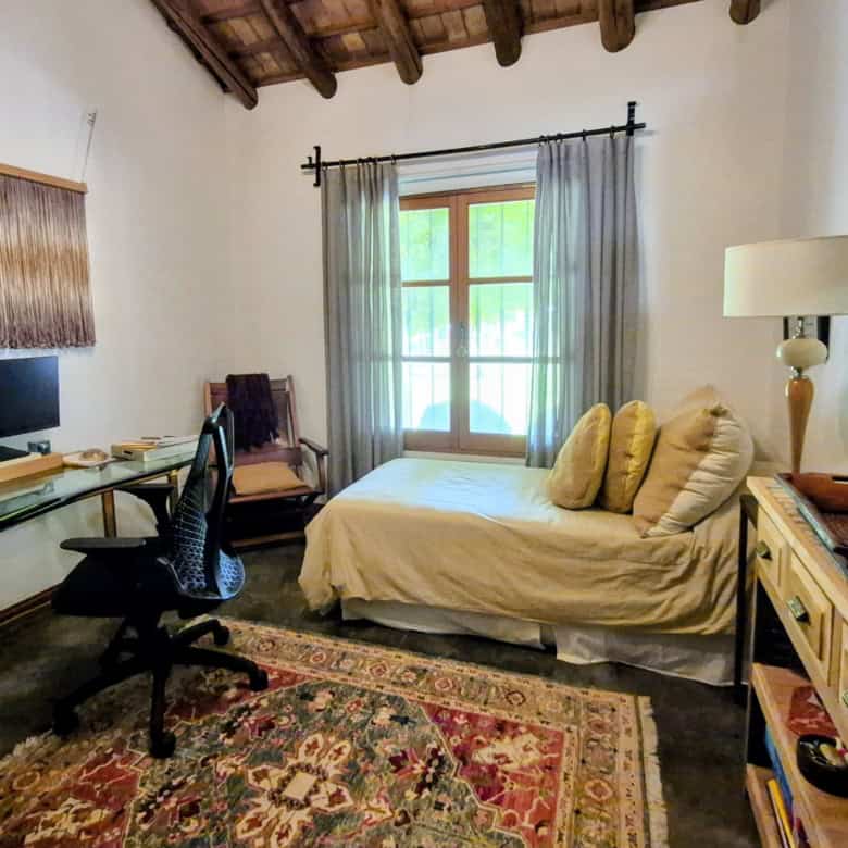 Comfortable bedroom with rustic charm, featuring a daybed, wooden furniture, and natural light from.