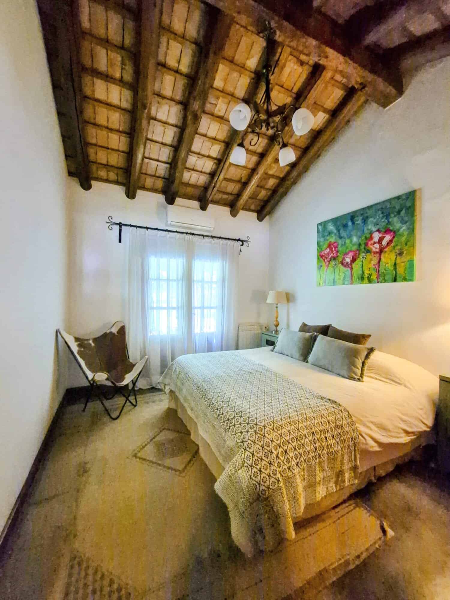 Charming Bedroom with Rustic Ceiling Beams Cozy bedroom featuring wooden ceiling beams, soft lighting, and a comfortable bed with decorative pi.