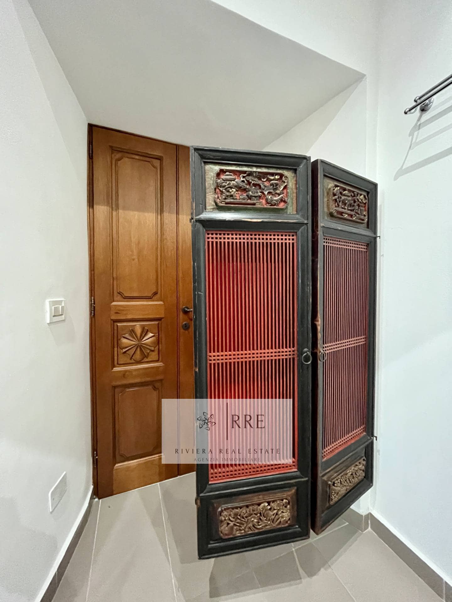 Traditional Asian wooden room divider with intricate carvings and red accents.