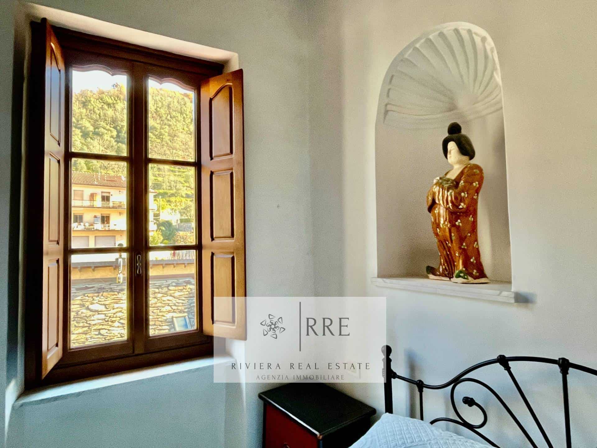 Geisha doll displayed in a niche with a window view of trees and buildings.