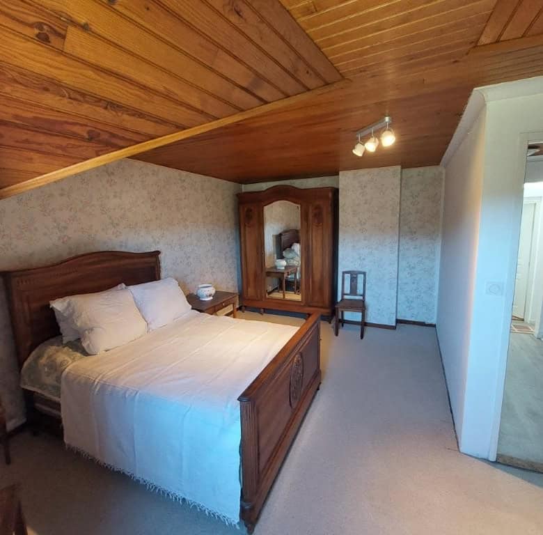 Cozy bedroom in a traditional farmhouse located in Madiran Village, France, featuring wooden accents.