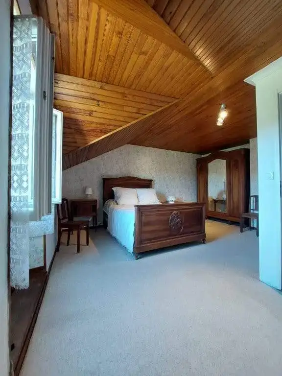 Cozy bedroom with wooden ceiling and vintage furniture in a French farmhouse.