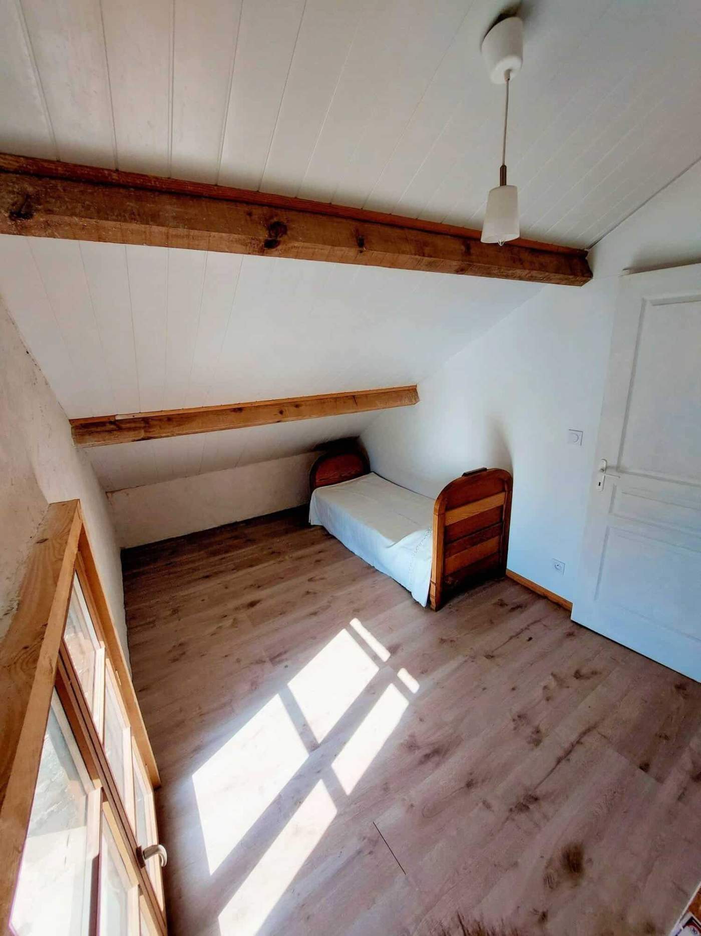 Charming Farmhouse Bedroom in Madiran France Cozy bedroom with sloped ceiling and wooden beams in a picturesque Madiran village farmhouse.